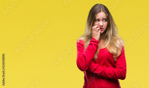 Young beautiful blonde woman wearing red sweater over isolated background looking stressed and nervous with hands on mouth biting nails. Anxiety problem.