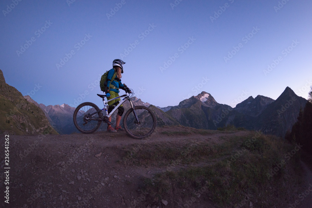Young woman walking along her mtb on backcountry route Young woman walking along her mtb on backcountry route