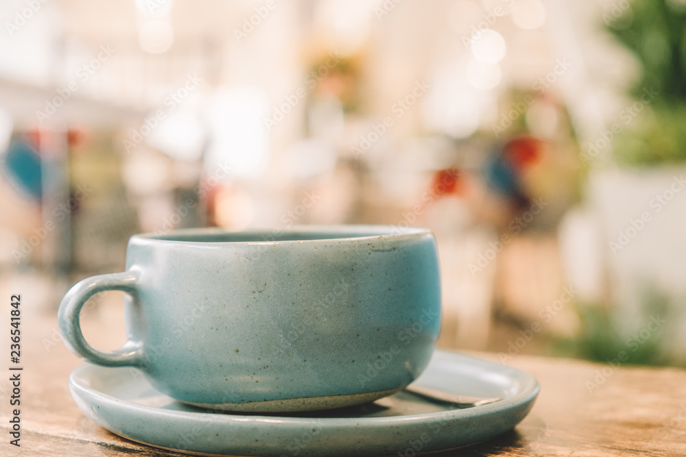 Ceramic Pastel Blue Tea cup on the wooden table with blur cafe background soft focus Ceramic Pastel Blue Tea cup on the wooden table with blur cafe background soft focus