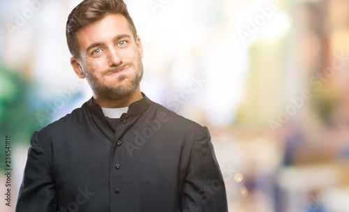 Young catholic christian priest man over isolated background puffing cheeks with funny face. Mouth inflated with air, crazy expression.