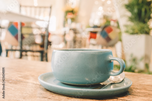 Ceramic Pastel Blue Tea cup on the wooden table with blur cafe background soft focus