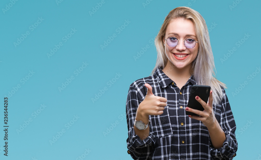 Young blonde woman texting sending message using smartphone over isolated background happy with big smile doing ok sign, thumb up with fingers, excellent sign Young blonde woman texting sending message using smartphone over isolated background happy with big smile doing ok sign, thumb up with fingers, excellent sign
