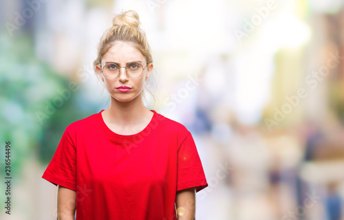 Young beautiful blonde woman wearing red t-shirt and glasses over isolated background skeptic and nervous, frowning upset because of problem. Negative person.
