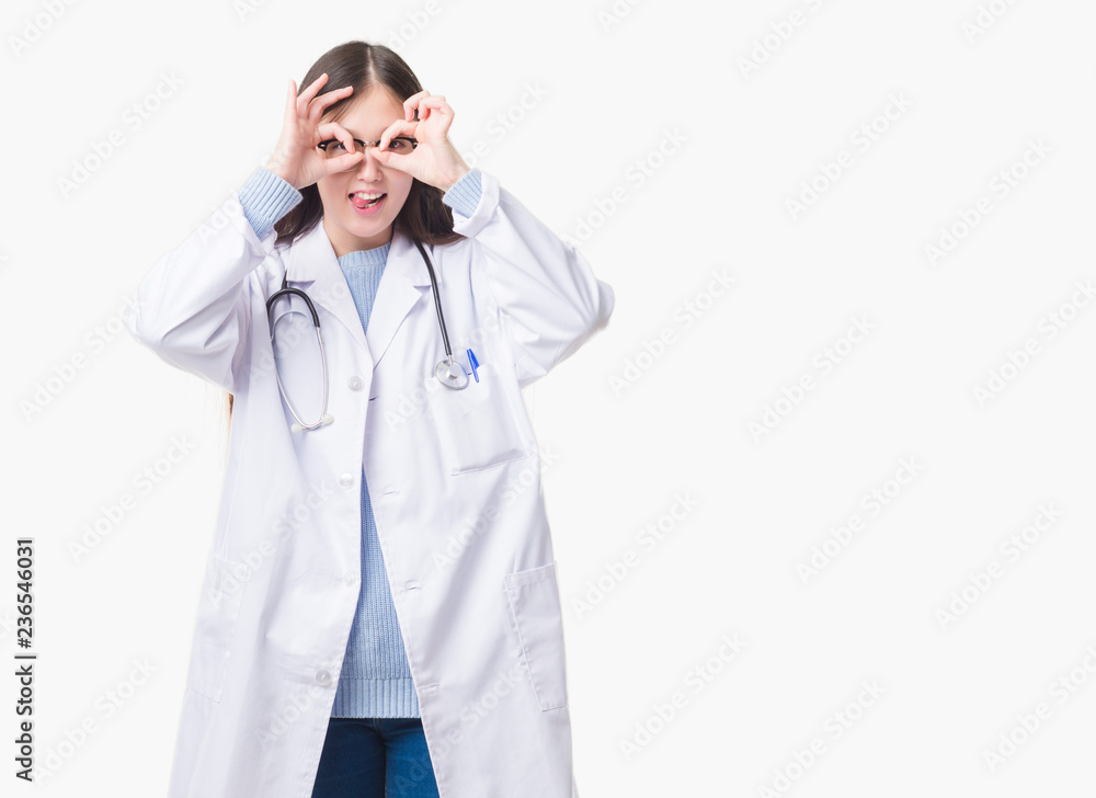 Young Chinese doctor woman over isolated background doing ok gesture like binoculars sticking tongue out, eyes looking through fingers. Crazy expression. Young Chinese doctor woman over isolated background doing ok gesture like binoculars sticking tongue out, eyes looking through fingers. Crazy expression.