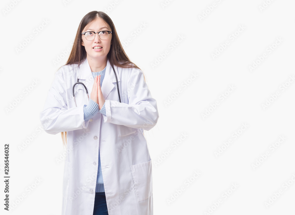 Young Chinese doctor woman over isolated background begging and praying with hands together with hope expression on face very emotional and worried. Asking for forgiveness. Religion concept. Young Chinese doctor woman over isolated background begging and praying with hands together with hope expression on face very emotional and worried. Asking for forgiveness. Religion concept.