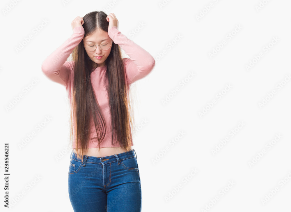 Young Chinese woman over isolated background wearing glasses suffering from headache desperate and stressed because pain and migraine. Hands on head. Young Chinese woman over isolated background wearing glasses suffering from headache desperate and stressed because pain and migraine. Hands on head.