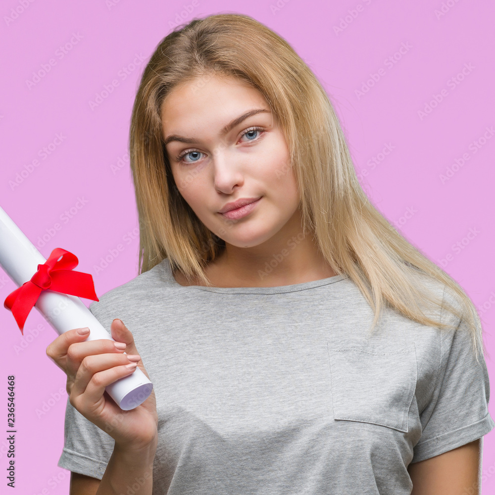 Young caucasian woman holding degree over isolated background with a confident expression on smart face thinking serious Young caucasian woman holding degree over isolated background with a confident expression on smart face thinking serious