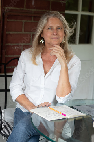 Blonde mature woman smiling with notebook