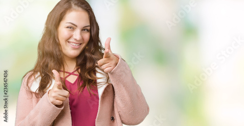 Beautiful plus size young woman wearing winter coat over isolated background pointing fingers to camera with happy and funny face. Good energy and vibes.