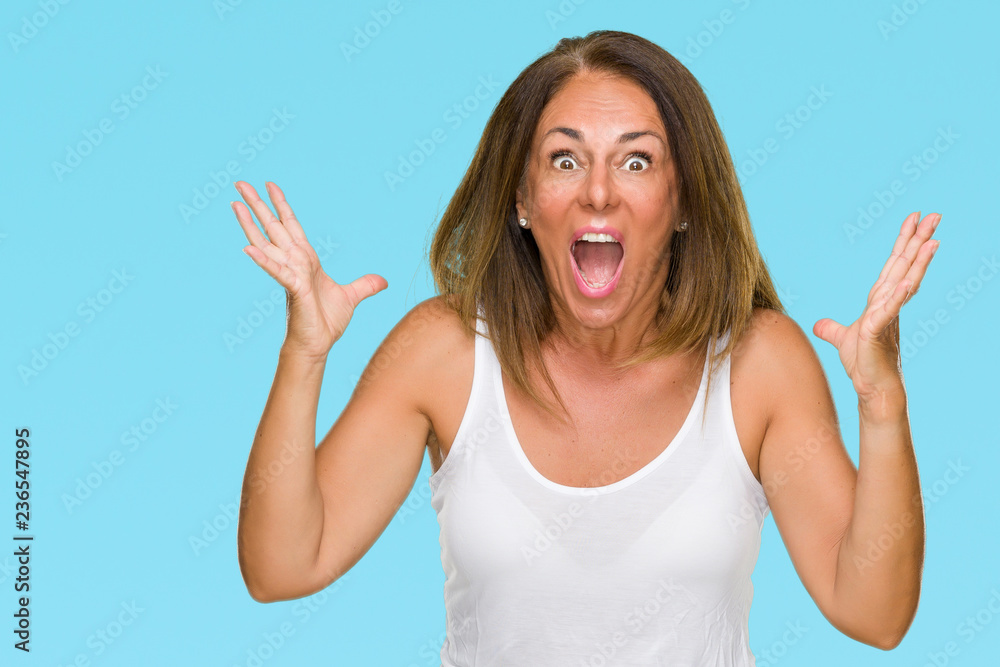 Beautiful middle age casual adult woman over isolated background celebrating crazy and amazed for success with arms raised and open eyes screaming excited. Winner concept Beautiful middle age casual adult woman over isolated background celebrating crazy and amazed for success with arms raised and open eyes screaming excited. Winner concept