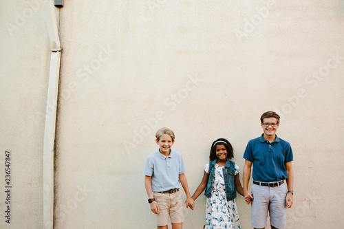 Multi-race siblings standing in front of a wall