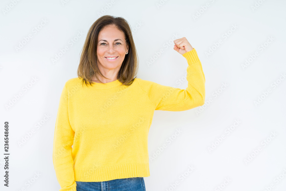Beautiful middle age woman wearing yellow sweater over isolated background Strong person showing arm muscle, confident and proud of power