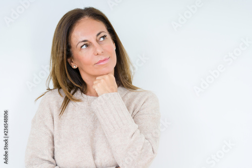 Beautiful middle age woman over isolated background with hand on chin thinking about question, pensive expression. Smiling with thoughtful face. Doubt concept.