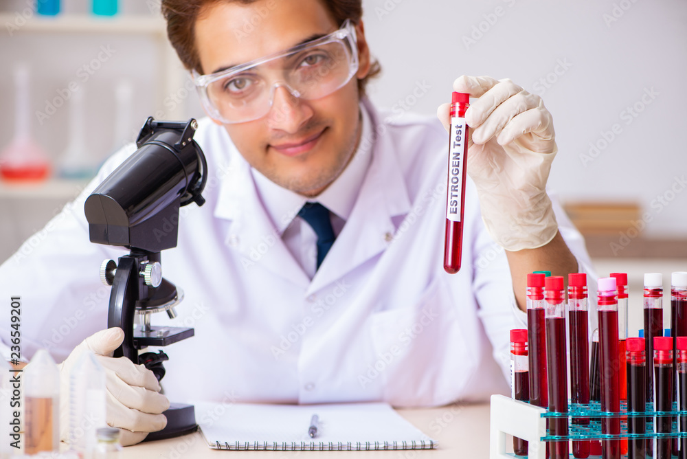 Young handsome lab assistant testing blood samples in hospital 
