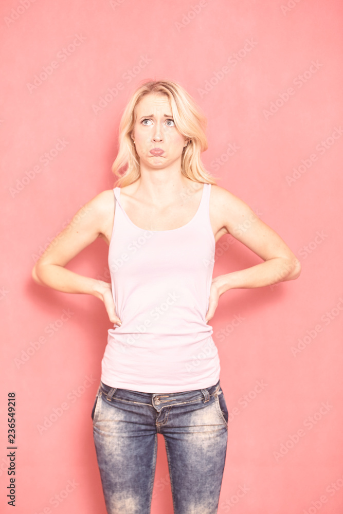 one young woman, dissatisfied emotion on her face, 20-29 years old, long blond hair. Shot in studio on pink background. one young woman, dissatisfied emotion on her face, 20-29 years old, long blond hair. Shot in studio on pink background.