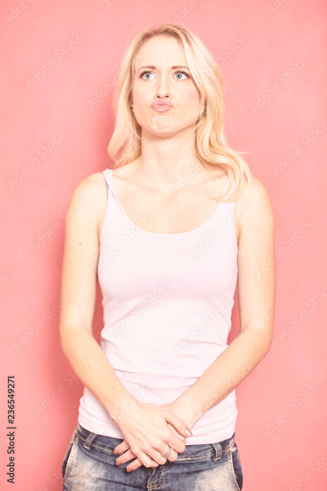 one young woman, puckering up her lips, hilarious. 20-29 years old, long blond hair. Shot in studio on pink background. one young woman, puckering up her lips, hilarious. 20-29 years old, long blond hair. Shot in studio on pink background.