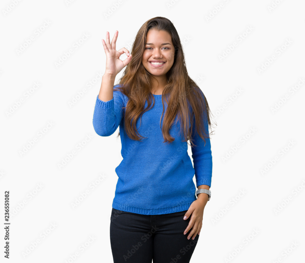 Fototapeta premium Young beautiful brunette woman wearing blue sweater over isolated background smiling positive doing ok sign with hand and fingers. Successful expression.