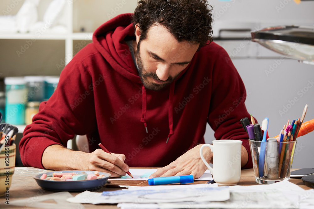 Artist In Sweatshirt Using Colored Pencil On Paper In Studio Artist In Sweatshirt Using Colored Pencil On Paper In Studio