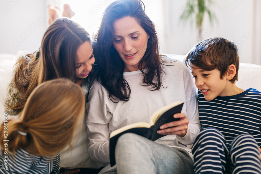 Mom and her kids reading a book at home in the morning. Mom and her kids reading a book at home in the morning.