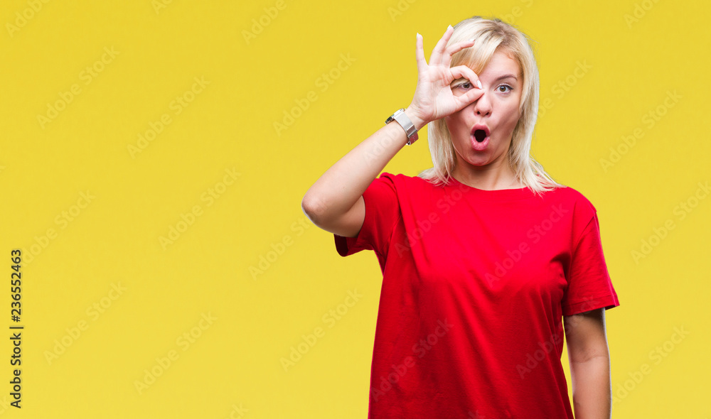 Young beautiful blonde woman wearing red t-shirt over isolated background doing ok gesture shocked with surprised face, eye looking through fingers. Unbelieving expression. Young beautiful blonde woman wearing red t-shirt over isolated background doing ok gesture shocked with surprised face, eye looking through fingers. Unbelieving expression.