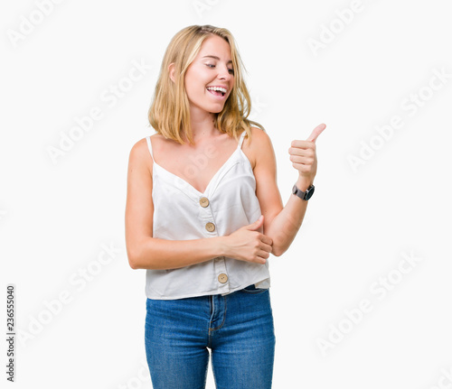 Beautiful young woman over isolated background Looking proud, smiling doing thumbs up gesture to the side