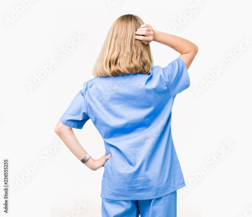 Beautiful young doctor woman wearing medical uniform over isolated background Backwards thinking about doubt with hand on head