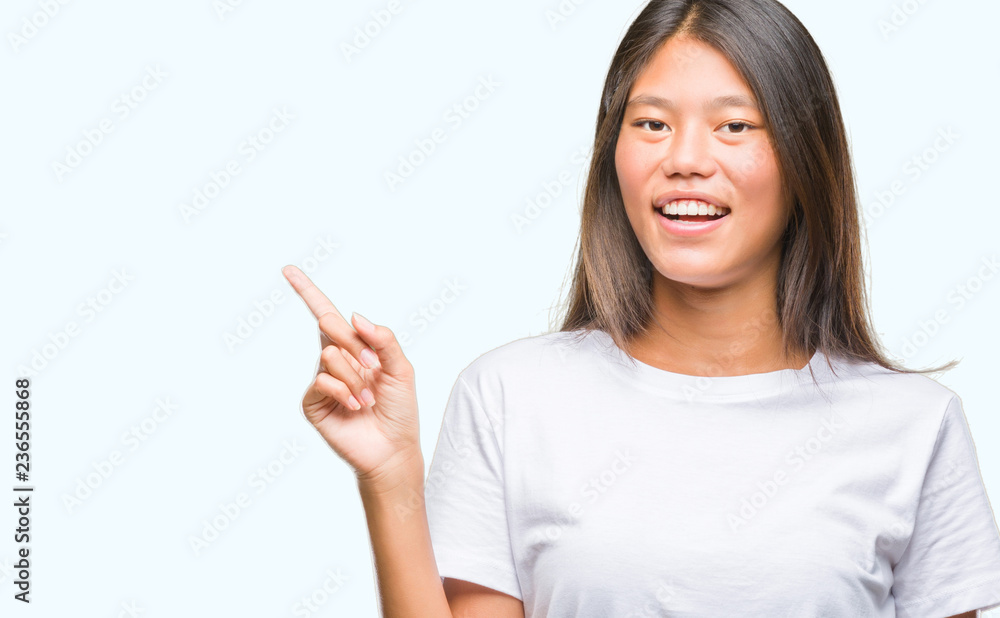 Young asian woman over isolated background with a big smile on face, pointing with hand and finger to the side looking at the camera. Young asian woman over isolated background with a big smile on face, pointing with hand and finger to the side looking at the camera.