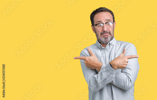 Handsome middle age elegant senior man wearing glasses over isolated background Pointing to both sides with fingers, different direction disagree photo