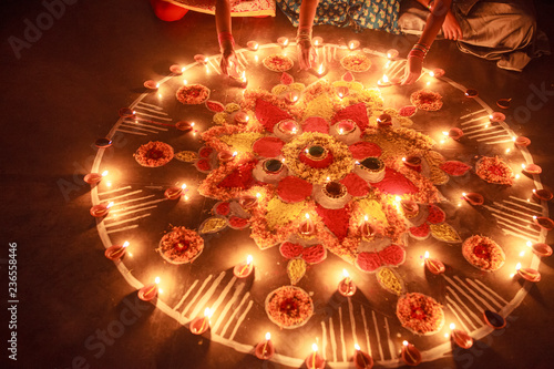 Woman enlightening Diya in Rangoli at Diwali Celebration