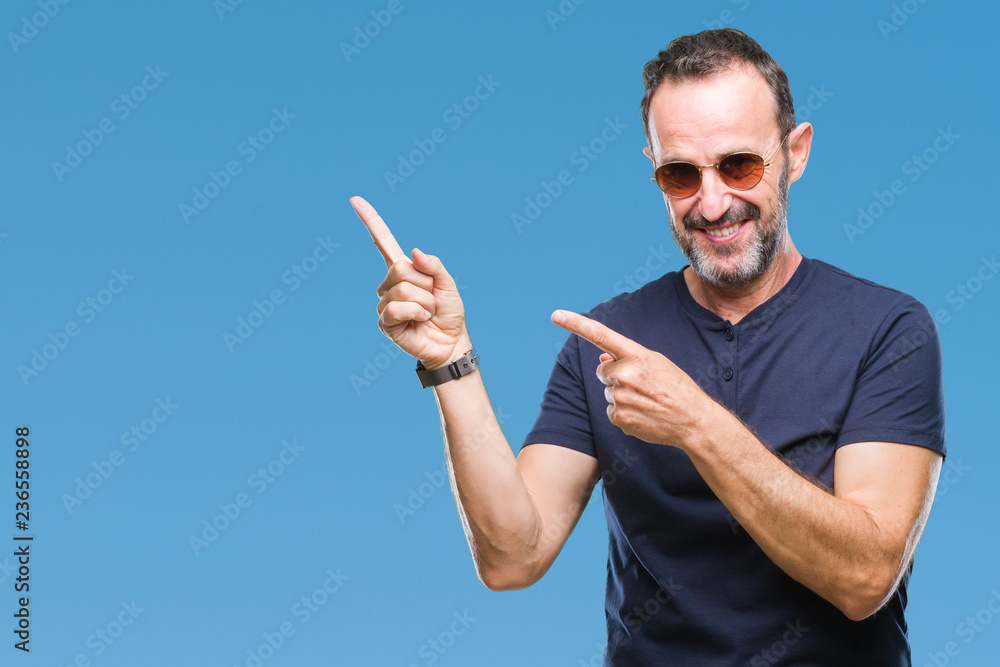 Middle age hoary senior man wearing sunglasses over isolated background smiling and looking at the camera pointing with two hands and fingers to the side. Middle age hoary senior man wearing sunglasses over isolated background smiling and looking at the camera pointing with two hands and fingers to the side.