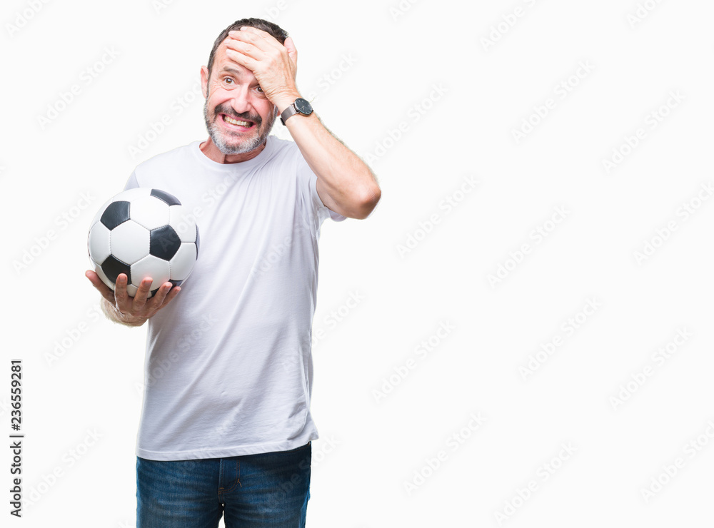 Middle age hoary senior man holding soccer football ball over isolated background stressed with hand on head, shocked with shame and surprise face, angry and frustrated. Fear and upset for mistake.