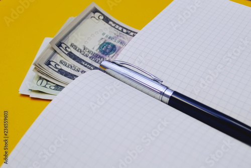 concept business time is money, a new notebook, pen fand money on a bright yellow background photo