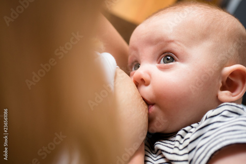 Baby looking at mother while breastfeeding photo