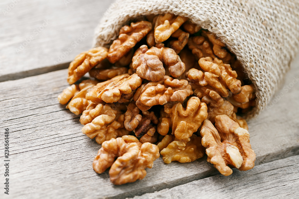 Walnuts in a burlap bag on a wooden gray background. Walnuts in a burlap bag on a wooden gray background.