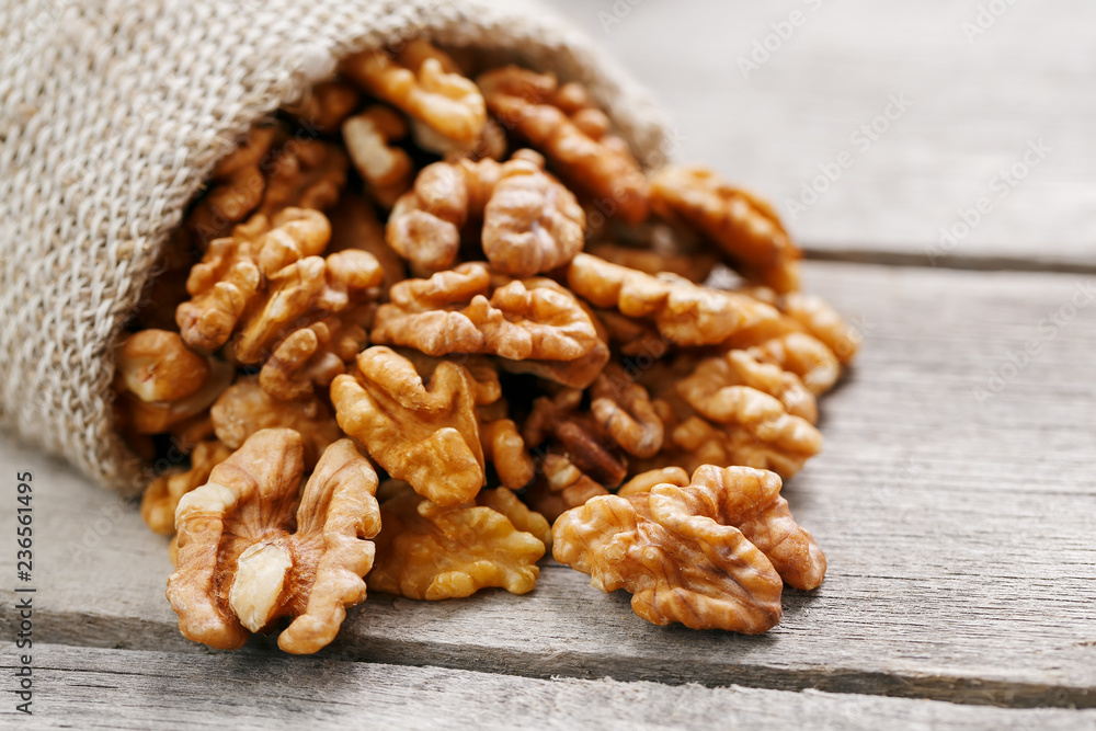 Walnuts in a burlap bag on a wooden gray background. Walnuts in a burlap bag on a wooden gray background.