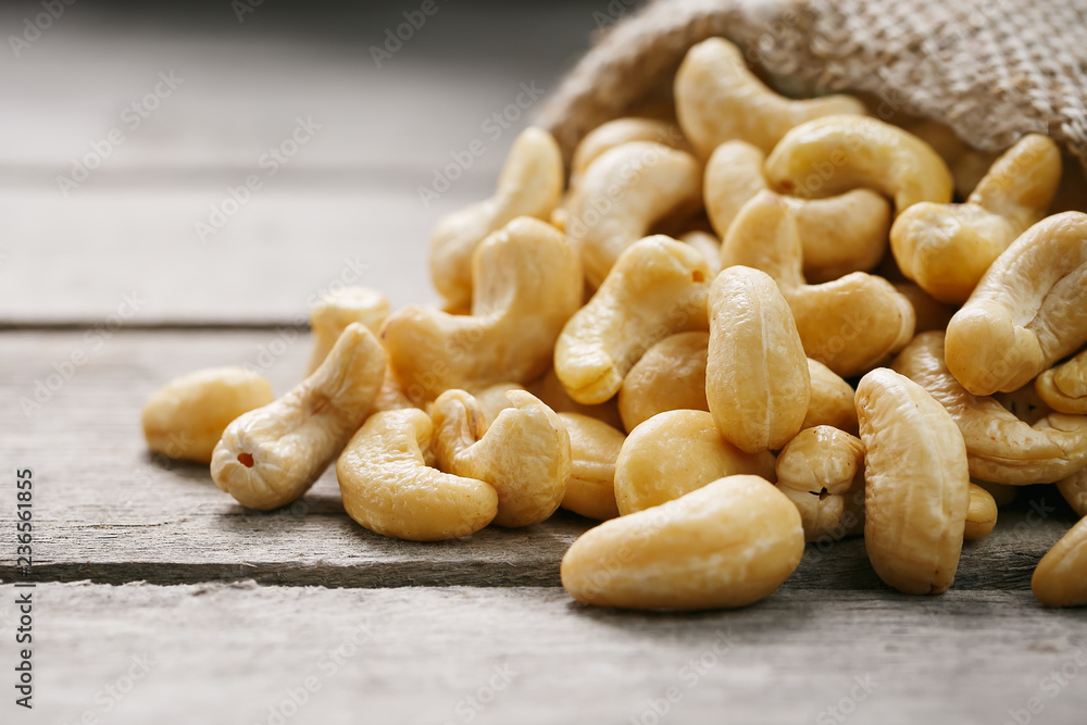 Cashew nuts in burlap bag on wooden gray background . Healthy food Cashew nuts in burlap bag on wooden gray background . Healthy food