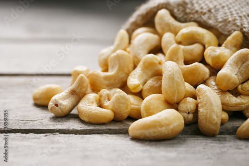 Cashew nuts in burlap bag on wooden gray background . Healthy food