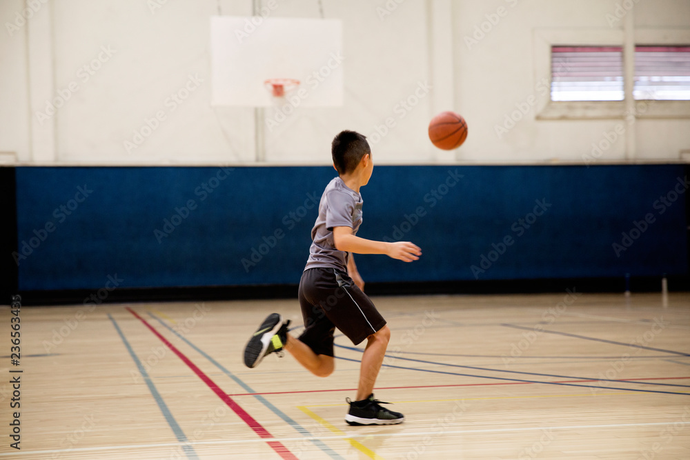Young asian basketball player running after his ball for a layup Young asian basketball player running after his ball for a layup