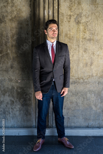 Portrait of young handsome businessman wearing suit in city