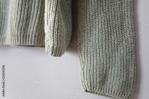 Light green sweater hanging on grey wall photo