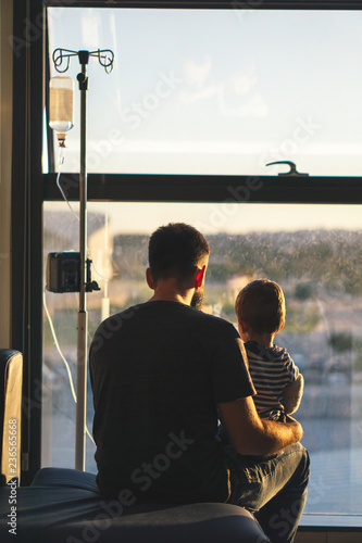 Back view of father and son sitting on the sofa in a  hospital photo