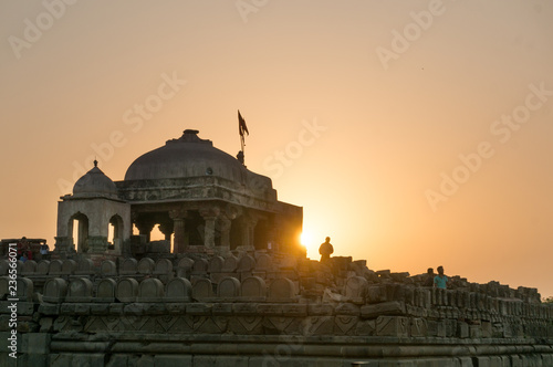 Old brown stone temple at Abhaneri shot at sunset. The temple near the baori with it's stone pillars, domed roof and the carved stone walls. This landmark and monument is a popular tourist place photo