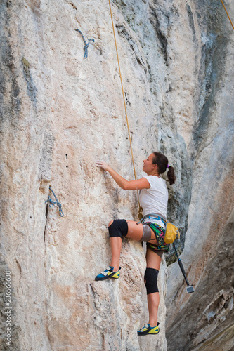 Young woman rock climbing on karst limestone white mountain in Thailand