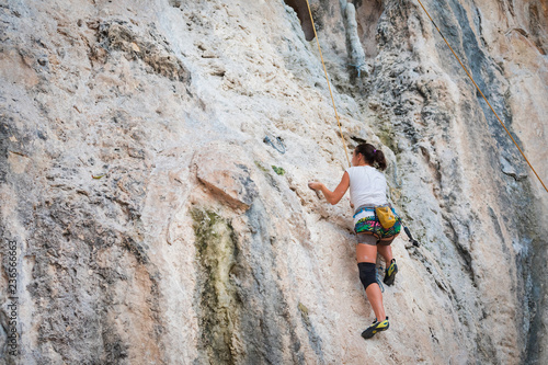 Young woman rock climbing on karst limestone white mountain in Thailand