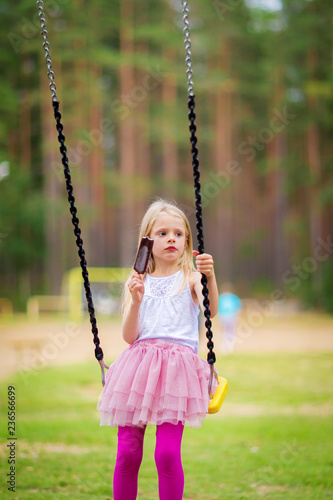 Little blonde girl smiling swinging outdoors on a playgroung