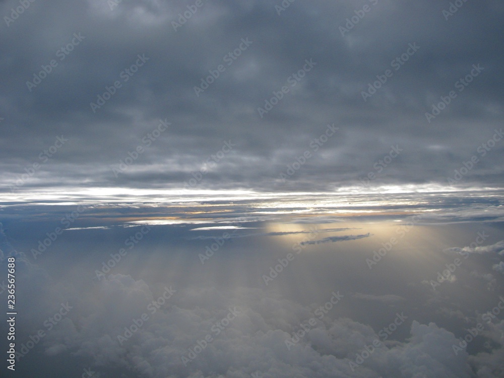 Flying between layers of clouds as sunbeams shine through