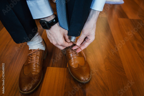 An elegant man puts on brown  leather  formal shoes. Tying shoes