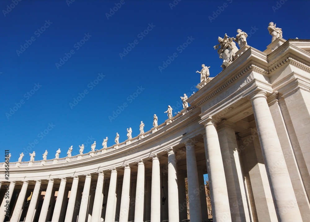 St. Peter's Basilica in Roma with columns and fountains on a sunny day with blue sky