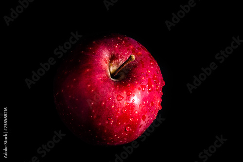 Red apple in water drops on a black background
