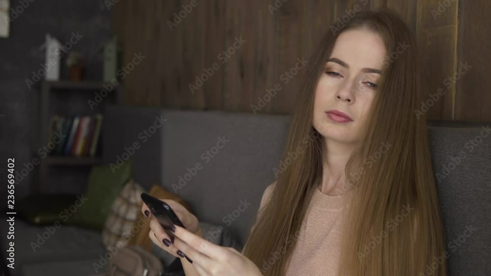 Smartphone girl using app on phone sitting in cozy cafe. Beautiful blonde woman with gorgeous natural long hair young casual professional on mobile phone. Smartphone girl using app on phone sitting in cozy cafe. Beautiful blonde woman with gorgeous natural long hair young casual professional on mobile phone.